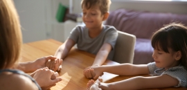 Zwei Kinder beten mit Eltern - alle halten sich an den H&auml;nden