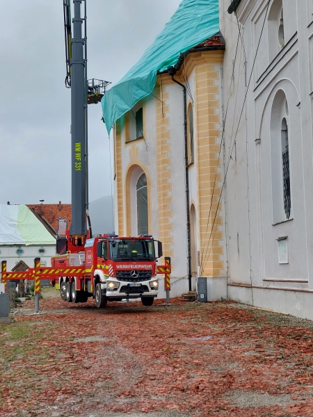 Eine türkisblaue Abdeckplane wird mit Hilfe eines Krans über der Anastasiakapelle der Benediktbeurer Basilika angebracht. 